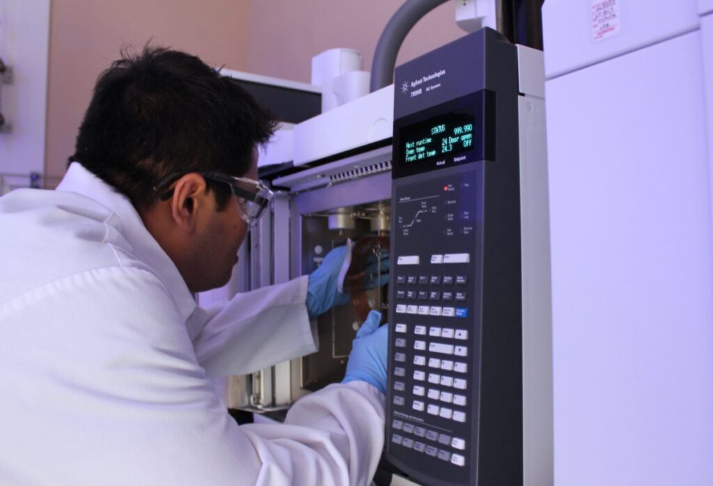 an image of one lab worker in white lab coat working with some complex laboratory machines