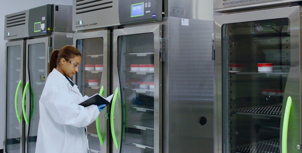 Woman in lab coat looking a folder in front of Laboratory Refrigerators